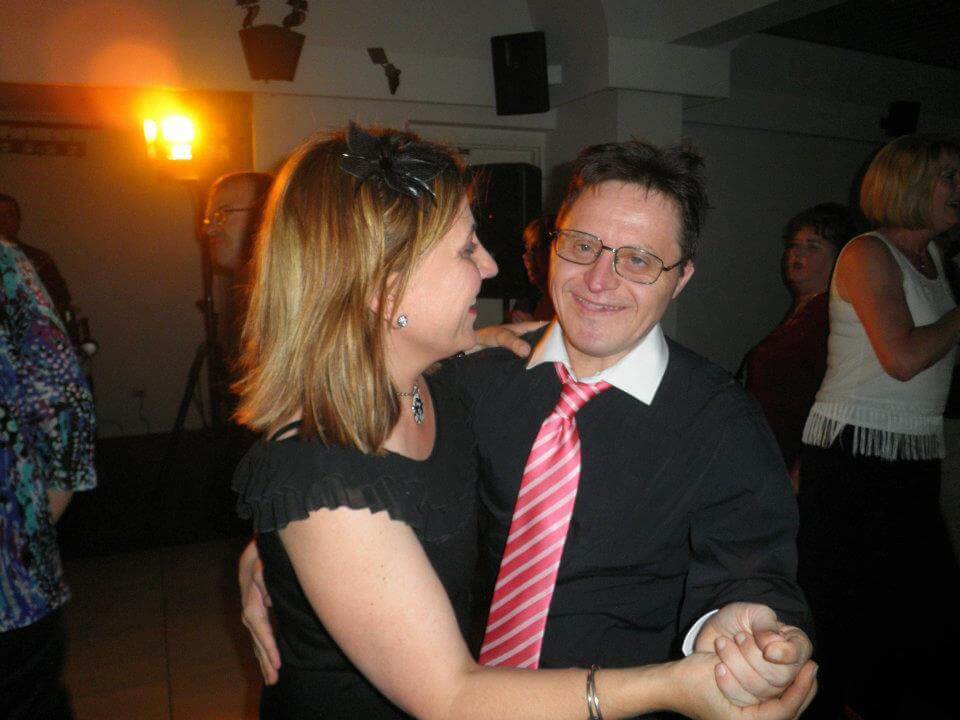 Louise at her brother's 50th birthday party Photo of Louise at her brother's 50th birthday party. She wears a black top with a black fascinator in her light brown shoulder length hair. She is dancing hand in hand with her brother.