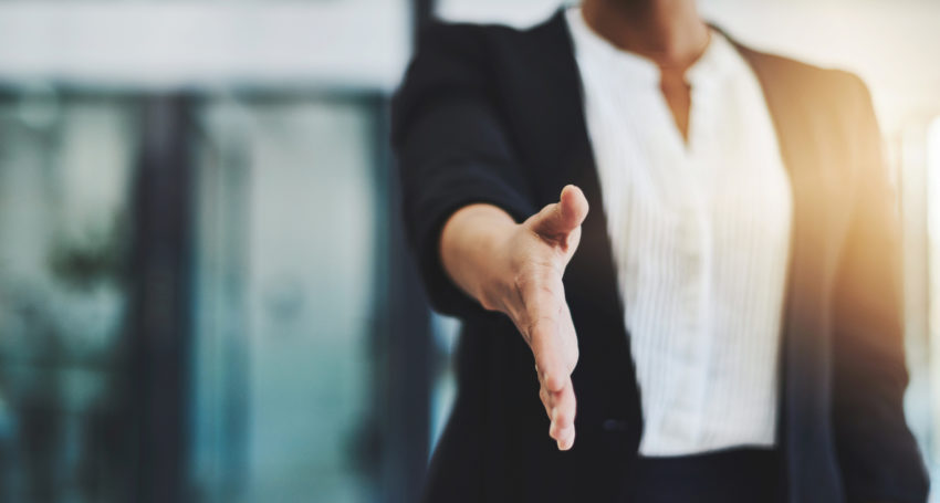 Person in business attire holding out a handshake.