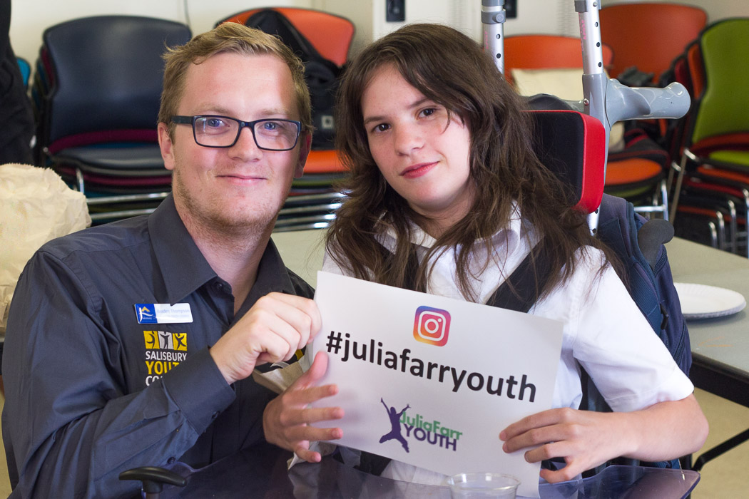 Two people holding a sign that says #JuliaFarrYouth