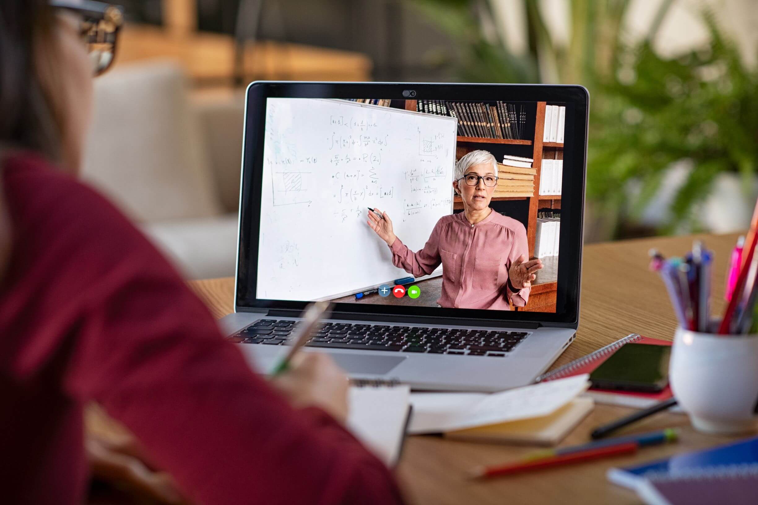 Image shows a woman watching a class through Skype on her laptop.