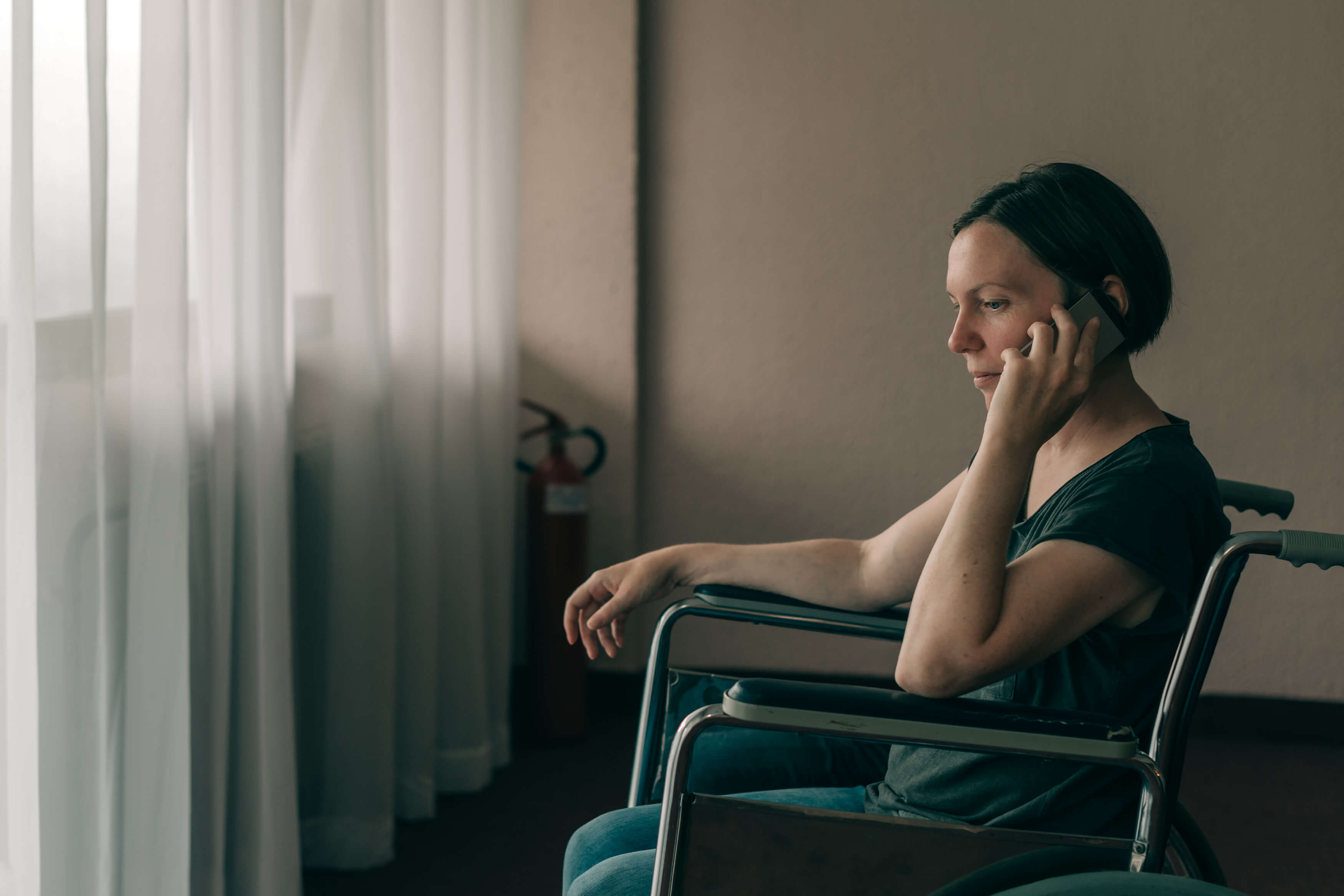 Image shows a woman in a wheelchair talking on the phone.