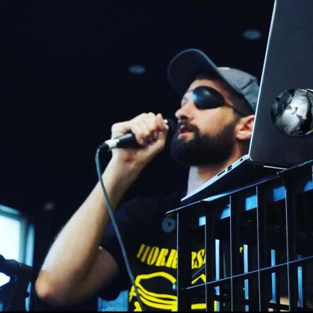 Photo shows Luke, who has a black patch over his left eye and a dark beard, performing at a show.