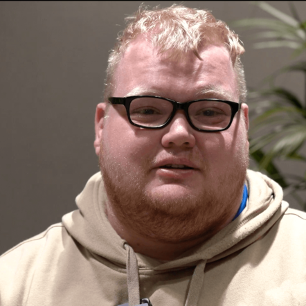 Photo of James, a man with white skin and light blonde hair, wearing glasses and a beige hoodie.