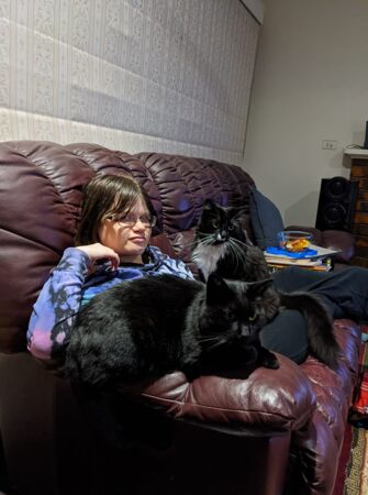 Leeanne relaxing on her couch at home with her two cats.