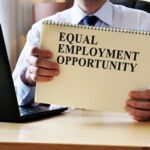 Photo of person holding a sign that says Equal Employment Opportunity.