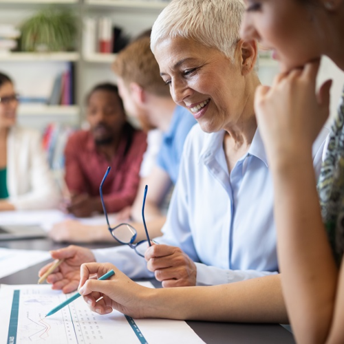 Photo shows a diverse group of people at a table working together.