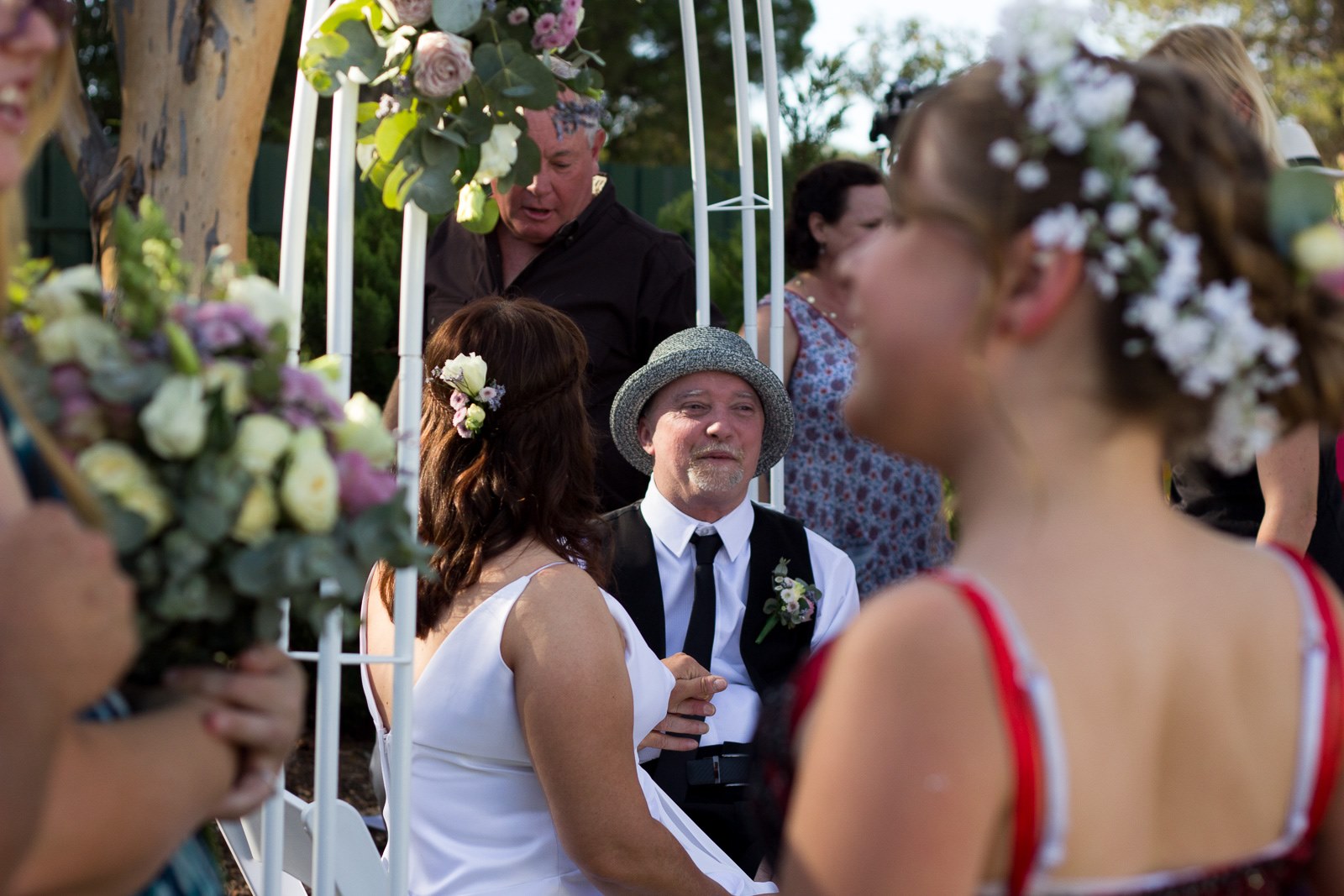 Stephen and Tracy holding hands under the wedding altar surrounded by people