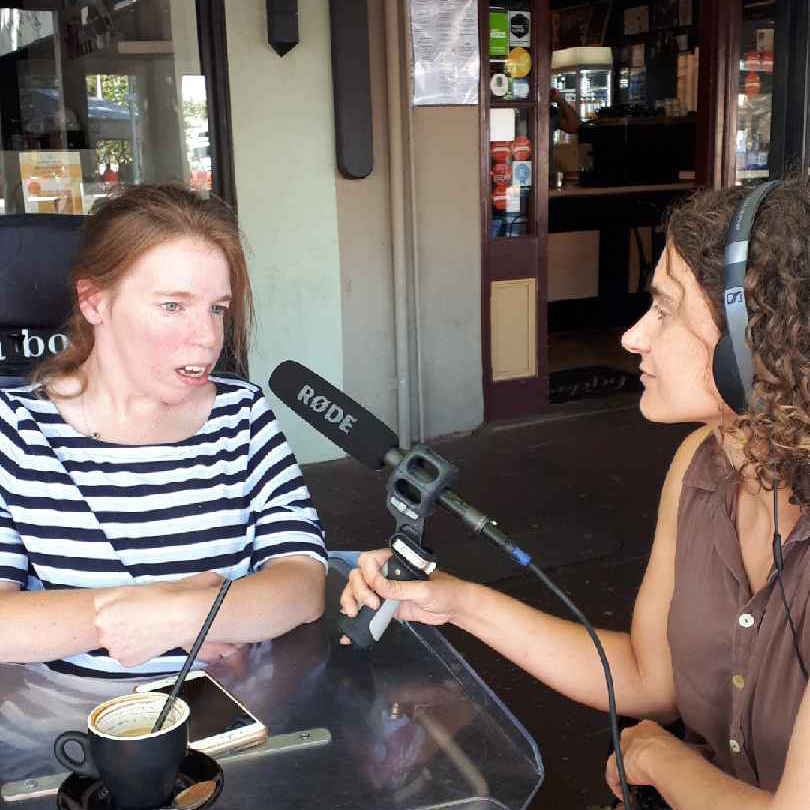 Georgia Horgan being interviewed at cafe while drinking a coffee with a straw