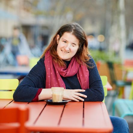 Ellen smiles at the camera. She's sitting at a table outdoors.