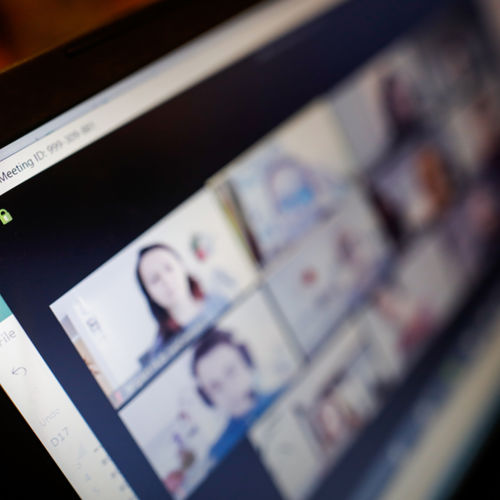 a laptop with a zoom meeting open showing multiple attendees on the screen.